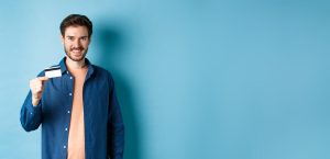 גבר מחייך מחזיק כרטיס אשראי