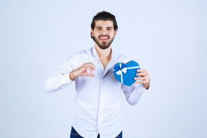 גבר מחייך מחזיק קופסא בצורת לב